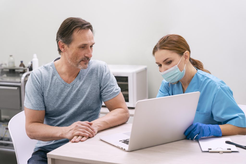 A middle aged man receiving therapy details from A DHA certified female medical staff.